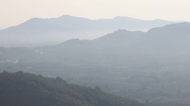 Natural video background of a high-angle atmosphere on a mountain that overlooks the surrounding scenery(mountains, trees,sea)from a scenic vantage point,with a wooden chair for sitting and resting