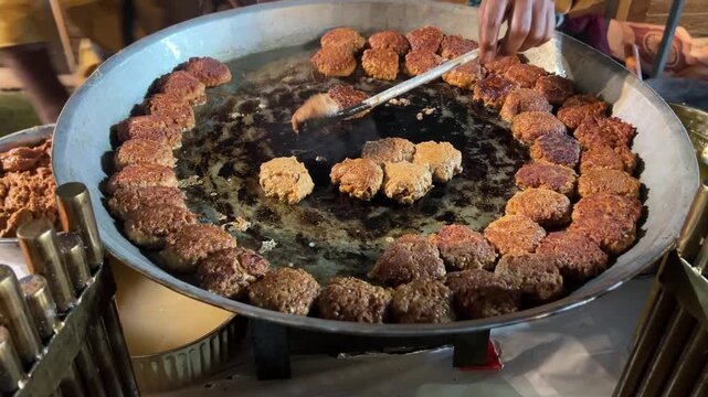 Sizzling street food: Authentic Galauti Kebabs being slow-cooked on a large iron Tawa at a roadside stall in India