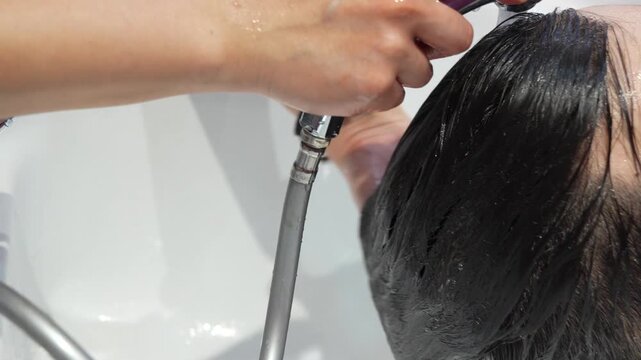 Hand massaging soapy hair of a client in a wash basin