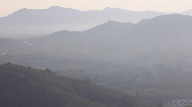 Natural video background of a high-angle atmosphere on a mountain that overlooks the surrounding scenery(mountains, trees,sea)from a scenic vantage point,with a wooden chair for sitting and resting