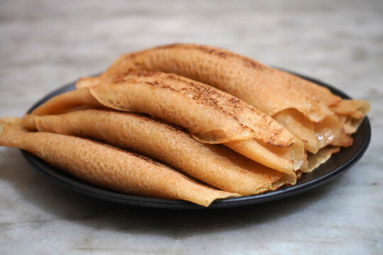 Side View of Traditional Bengali Sweet Patisapta Pitha Served on a Black Plate