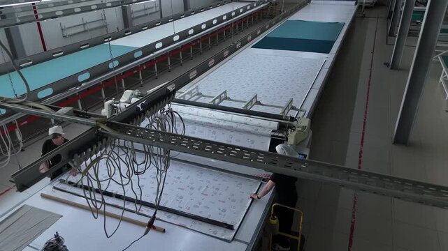 Industrial quilting machine stitching fabric at a textile factory, top view of automated production