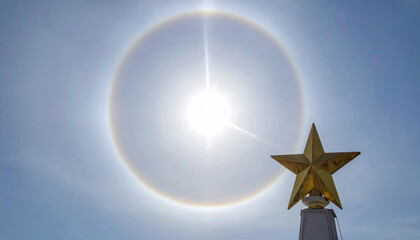 Fototapeta premium A Golden Star Topper Overwhelmed by a Vivid Sun Halo and Rainbow Ring