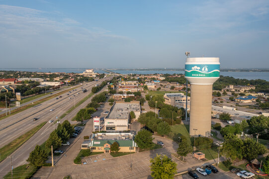 Aerial Drone View of Rockwall Water Tower and Surrounding Parking Lots and Buildings With Lake in the Distance in Rockwall, Texas