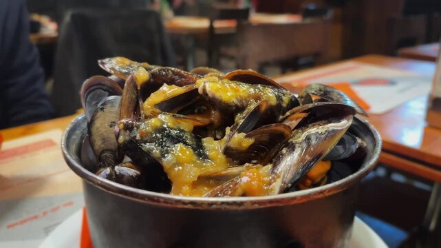 Steaming mussels served with a spicy onion sauce in a restaurant specializes in mussel dishes, tender, rich, and irresistibly tasty. High quality 4k footage
