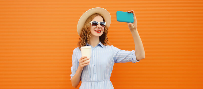 Joyful happy young woman smiles taking selfie with phone, modern cheerful girl in summer tourist hat