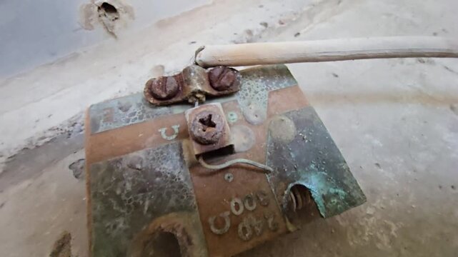 Macro shot of a corroded water heater electrical connector with heavy rust and green oxidation. Close-up view highlights damaged terminals and resistance markings on a weathered metal surface.