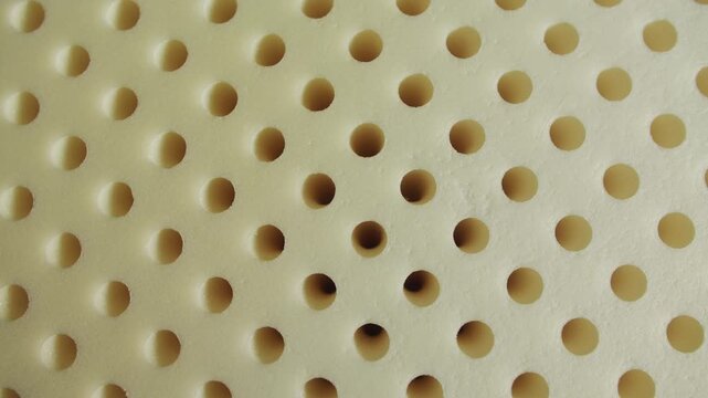 Close-up of a memory foam pillow layer with perforated surface. Soft breathable material with pressure-relief and shape-retaining properties. High quality 4k footage