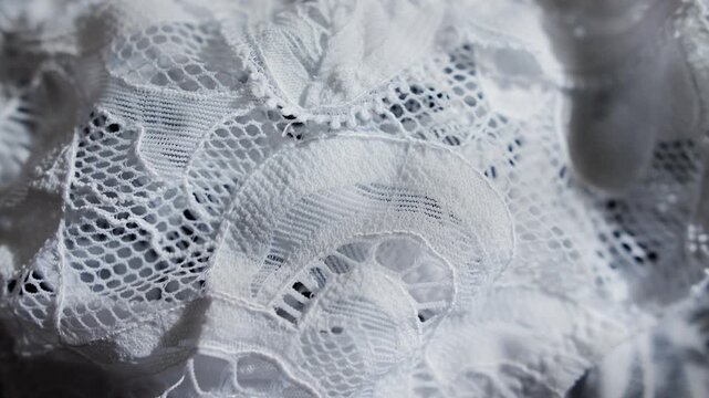 Close-up of white lace fabric, highlighting its delicate texture and intricate patterns. Perfect for fashion, wedding themes, clothing design, backgrounds. High quality 4k footage