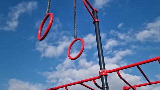 Gymnastic rings for the street. Open-air sports grounds. Red pull-up rings on the sky background. Public space for training. Concept of physical activity development. Zones for various exercises