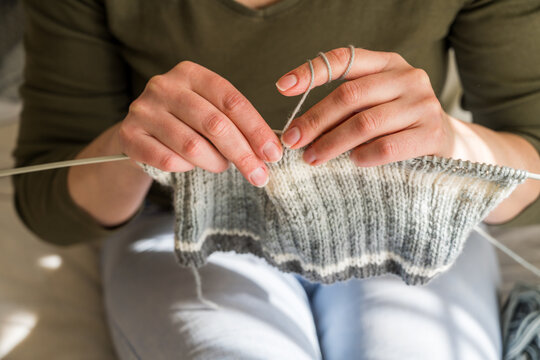 Woman knitting, close-up hands with yarn and knitted scarf. Handicraft hobby concept