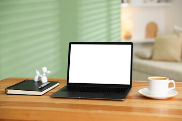 Naklejka premium Stylish workplace with laptop, stationery and cup of coffee on wooden desk indoors