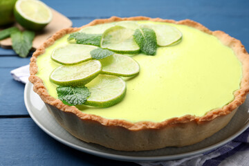 Tasty lime pie with fruit slices and mint leaves on blue wooden table, closeup © New Africa