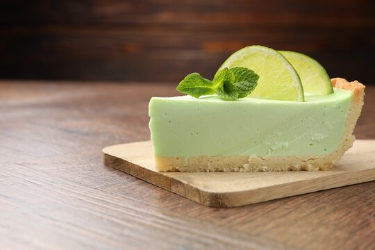 Piece of delicious lime pie with mint on wooden table, closeup. Space for text