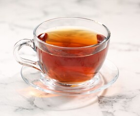 Fototapeta premium Tasty tea in glass cup on white marble table, closeup