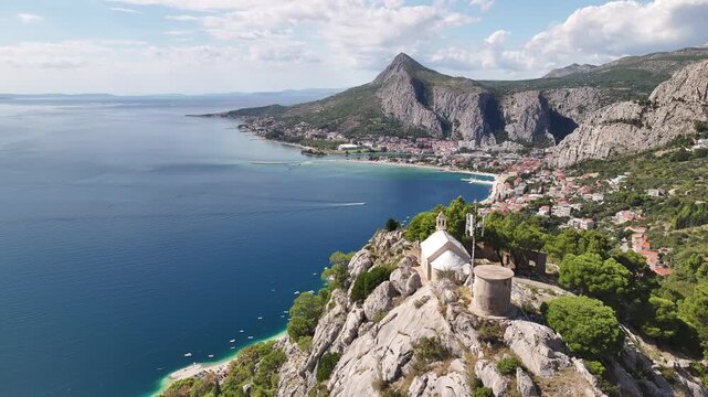 Drone aerial of a church above Omis offering a breathtaking view of the town, river and Adriatic Sea.