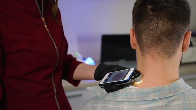 Dermatologist examining patient's mole with a modern dermatoscope