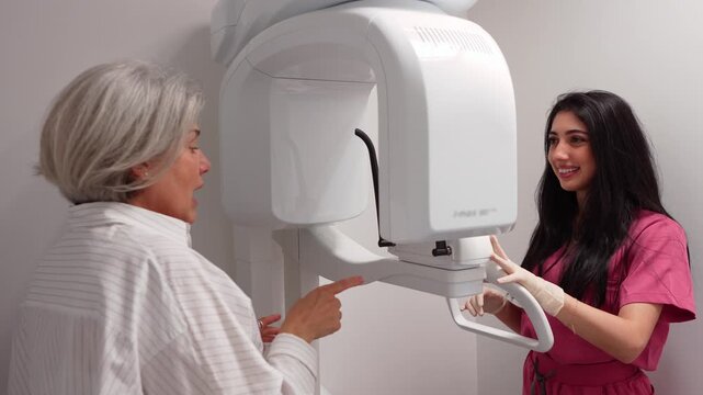 Professional dental assistant positioning a senior woman in a modern 3d cone beam computed tomography machine for an oral x ray