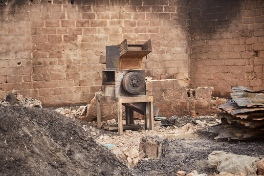 Kano, Nigeria - 27 January 2024: View of an aged, weathered machine, resting on a crude wooden frame amid a rubble-strewn landscape with brick walls.