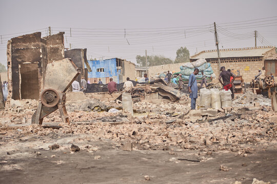 Kano, Nigeria - 27 January 2024: View of the fire-ravaged Dakata market, its charred remains a stark contrast against the pale sky, and people surveying the scene.