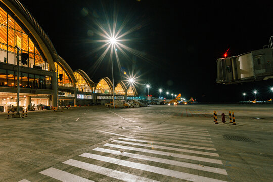 Lapu-Lapu, Philippines - 20 July 2018: View of the Mactan-Cebu International Airport's Terminal 2 glows warmly against the dark night sky, with bright lights illuminating the crosswalk.
