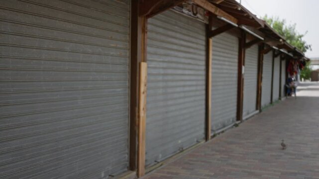 Closed corrugated metal shop shutters rendered in soft defocused blur along a quiet street; background backplate copyspace template.