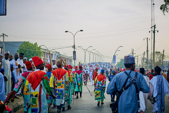 Kano, Nigeria - 17 March 2022: View of a vibrant procession along Emir places road to Kofar Wambal, a river of colorful robes flowing towards the horizon.