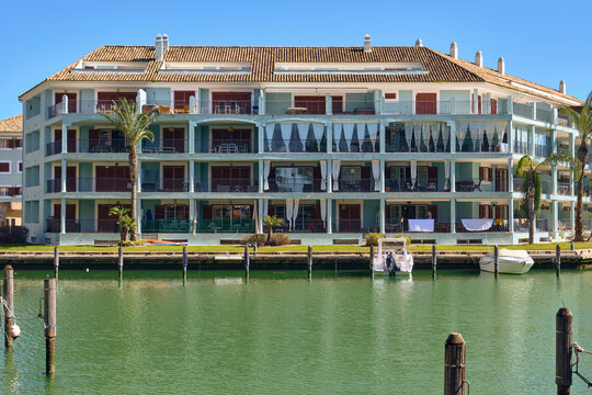 Sotogrande, Spain - 22 February 2026: View of the tranquil waterfront where turquoise buildings meet emerald waters, punctuated by the dark wood of docks and masts.