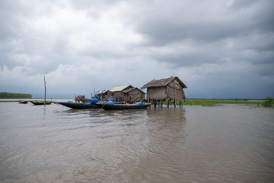Khulna, Bangladesh - 13 July 2025: View of stilted huts and boats float on the water under a brooding sky, reflecting the serene yet resilient spirit of its inhabitants.