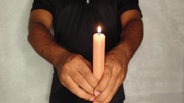Closeup of person hand holding burning wax candle light. Iran or middle east war impact, energy crisis, blackout, power outage, global crude oil shortage and gas or fuel supply disruption concept.