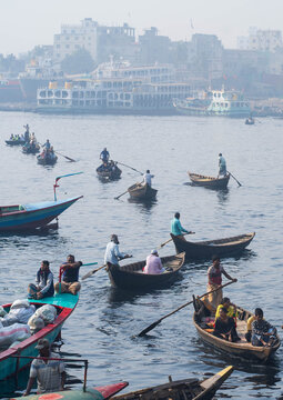 Keraniganj, Bangladesh - 11 February 2023: View of the river bustling with colorful boats and the distant cityscape fading into the misty horizon.