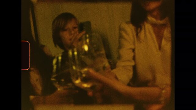 Authentic Super 8mm footage of friends celebrating. A person opens a champagne bottle, and the group joyfully toasts. Warm, grainy, nostalgic home movie style for a retro party scene at night