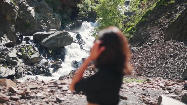 4K shot of defocused girl standing against waterfall in Pangi Valley, Himachal Valley, India. Beautiful waterfall cascade during summer season. Travel and vacation concept.