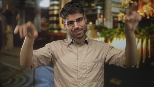 Young hispanic man showing rock horns with hands in church building; playful energy youthful spirit.