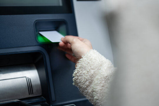 Person inserting atm card into cash machine slot