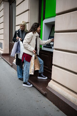 Fototapeta premium Women shopping, withdrawing money from atm cash machine