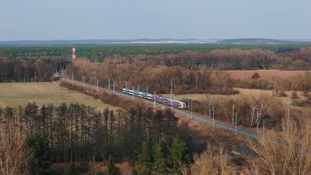 Aerial drone view of modern double-deck passenger train passing through rural landscape, Czech Republic