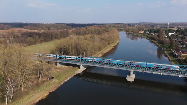 Aerial drone view of railway bridge over Elbe river with passenger train, Czech Republic