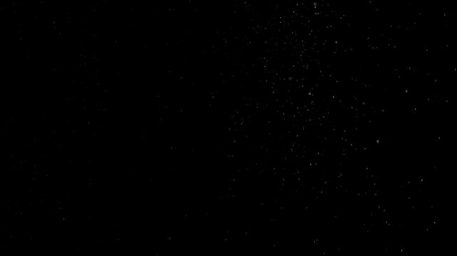 White particles floating up out of darkness