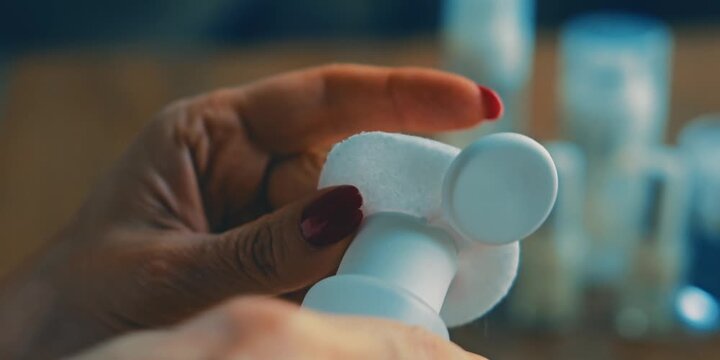 woman cleaning nail polish with cotton pad