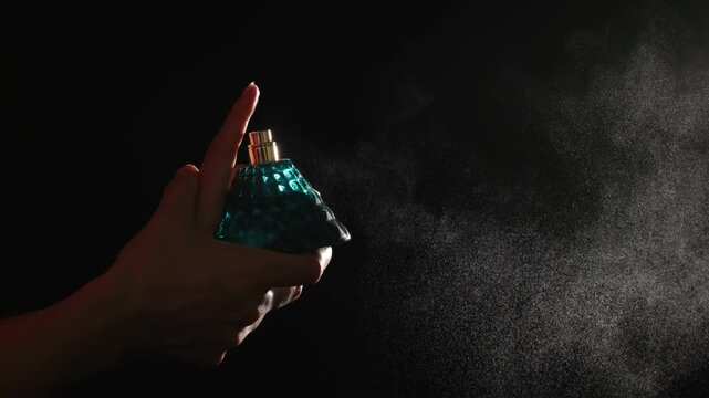 spraying perfume bottle on black background