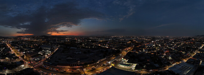 Panoramic cityscape at dusk with urban lights and dramatic sky © ANGEL