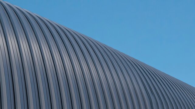 A close-up view of a modern building's curved metal roof against a clear blue sky