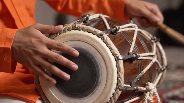 Close-up of a musician's hands playing a traditional wooden dholak drum with vibrant orange tones, celebrating baisakhi.