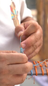 Craftsman meticulously weaving a colorful waxed thread bracelet with intricate patterns