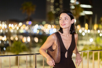 Fototapeta premium Slender female brunette walks in vicinity of Citadel Park, spends time in motion, walks and enjoys sunny warm day. Carefree, lively nightlife, promenade.