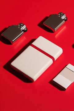 Retro Metal Pocket Lighters and Minimal Cigarette Case on Bold Red Background , Vintage Smoking Accessories Flat Lay with Dramatic Shadows, Modern Product Display Concept