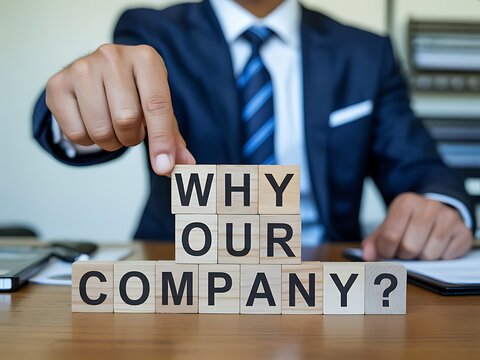 Professional businessman asking Why Our Company with wooden blocks on office desk
