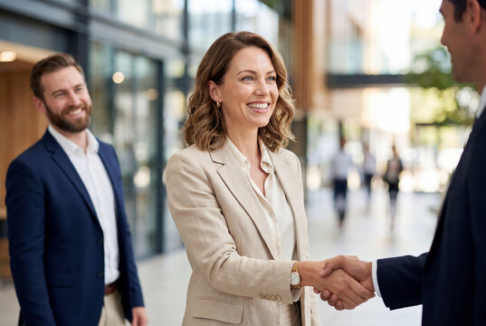 Businesswoman shakes hands with colleague in modern office atrium