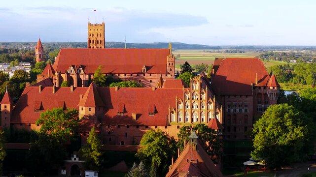 Castle of the Teutonic Order in Malbork by the Nogat river at sunset. Poland